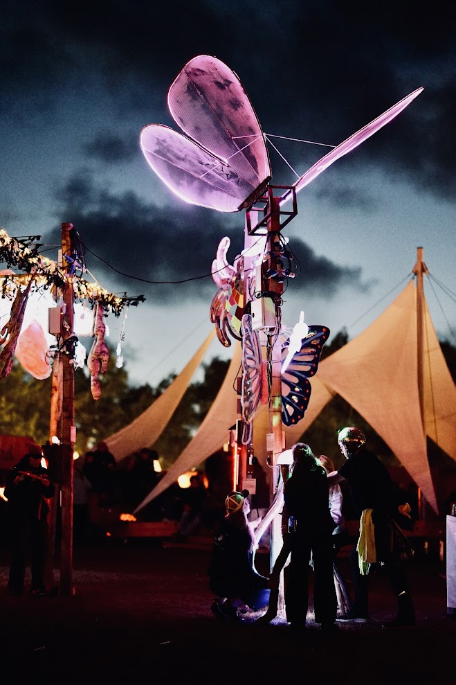 Pale illuminated butterfly wings and exposed frame above festival visitors